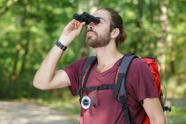 男人在树林里透过双筒望远镜看东西 — 图库照片