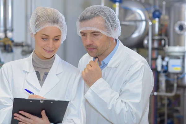穿着实验室外套在工厂工作的男男女女 — 图库照片