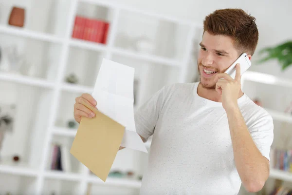 Hombre Sonriente Hablando Por Teléfono Sosteniendo Papeles — Foto de Stock