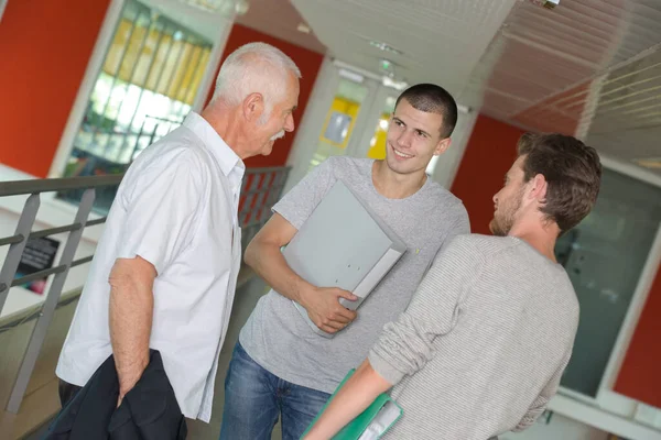 Dois Alunos Sexo Masculino Conversando Com Professor Sênior Corredor — Fotografia de Stock