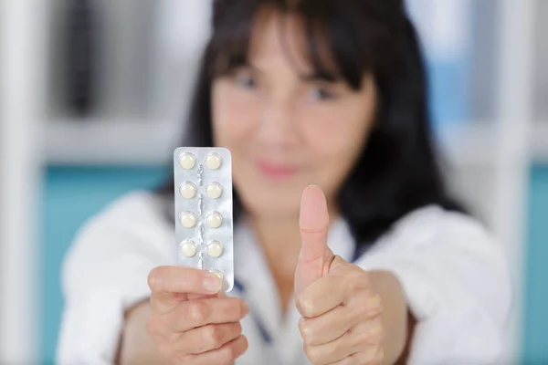 Zralá Žena Lékař Drží Pilulku Ukazuje Palce Nahoru — Stock fotografie