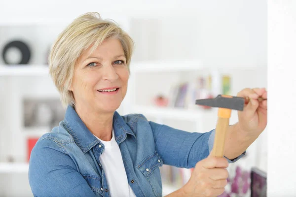 Reife Frau Hämmert Einen Nagel Weiße Wand — Stockfoto