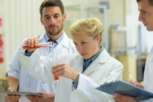Kvinnlig Forskare Bedömning Häller Orange Vätska Glasröret — Stockfoto