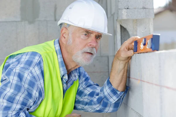 Construtor Sênior Olhando Nível Uma Parede Concreto — Fotografia de Stock