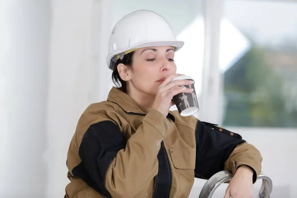 将咖啡放在室内的女建筑工人 — 图库照片