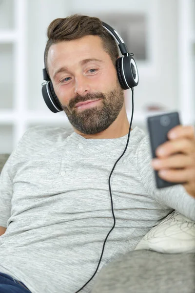 Uśmiechnięty Mężczyzna Telefonem Komórkowym Słuchawkami Domu — Zdjęcie stockowe