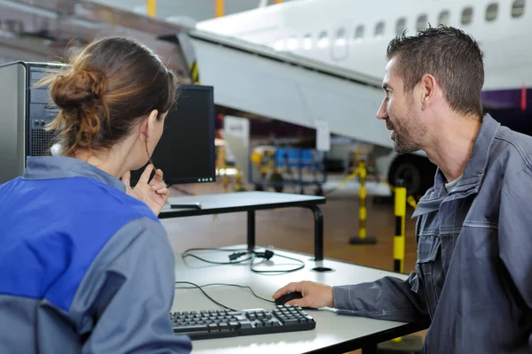 technicians using computer in aircraft hangar