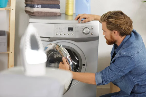 man near the washing machine with laundry basket