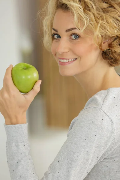 Kvinna Med Vågigt Hår Poserar Med Ett Äpple Hemma — Stockfoto