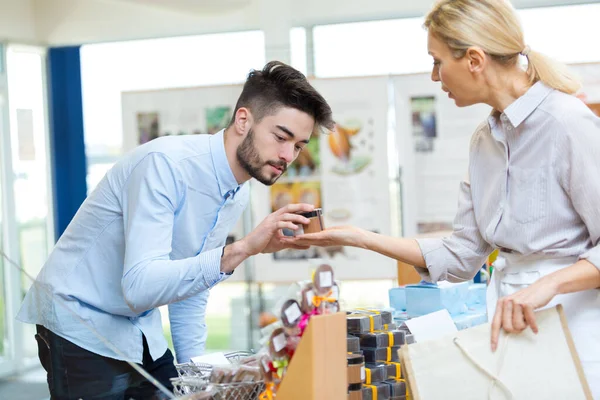 Πελάτης Εξετάζει Προϊόν Που Κατέχει Στο Χέρι Λιανοπωλητές — Φωτογραφία Αρχείου