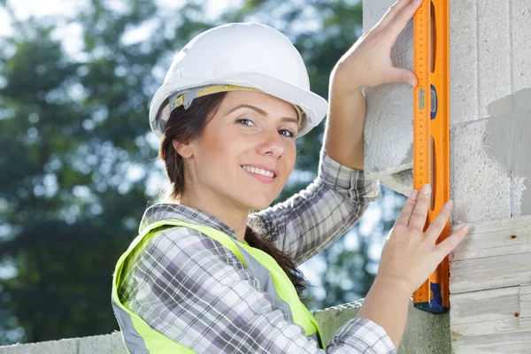 Glückliche Bauarbeiterin Die Mit Einer Ebene Einer Wand Arbeitet — Stockfoto