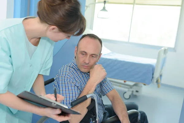 Krankenschwester Zeigt Einem Mann Rollstuhl Klemmbrett — Stockfoto