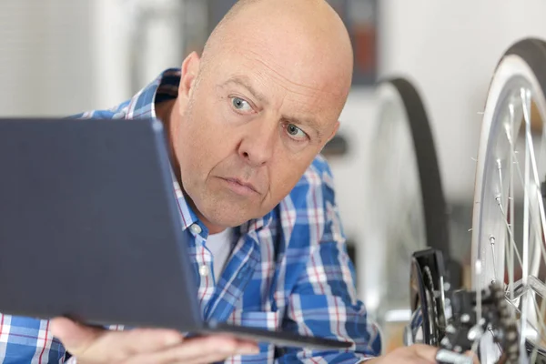 Man Die Een Laptop Gebruikt Thuis Een Fiets Repareren — Stockfoto