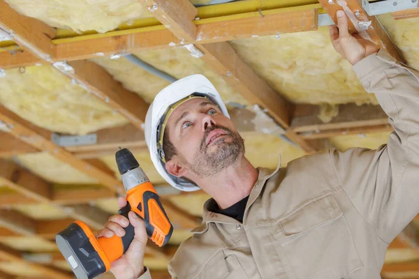 木製の天井の枠組みにドリルを使う男性建築家 — ストック写真