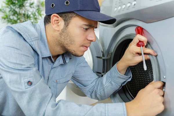 concentrated plumber with clipboard near washing machine
