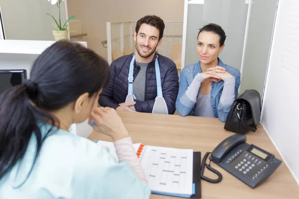 Jovem Casal Conversando Com Recepcionista Hospital — Fotografia de Stock