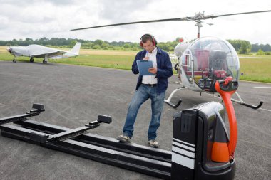 worker with clipboard writing next to helicopter trailer clipart