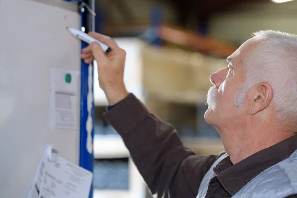 Senior Man Writing Factory Board — Stock Photo, Image