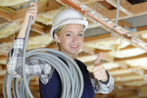 女性電気技師はケーブルを親指を立てて屋根に送り — ストック写真