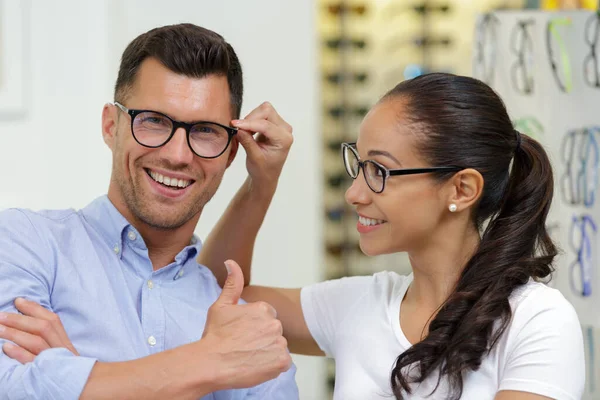 妇女和男子在光学商店里挑选新眼镜 — 图库照片