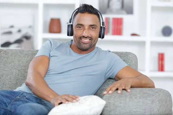 Mężczyzna Słuchawkach Słuchając Muzyki Siedzącej Kanapie — Zdjęcie stockowe