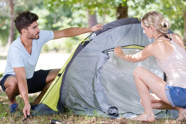 森でテントを作るパートナーを助ける女性は — ストック写真