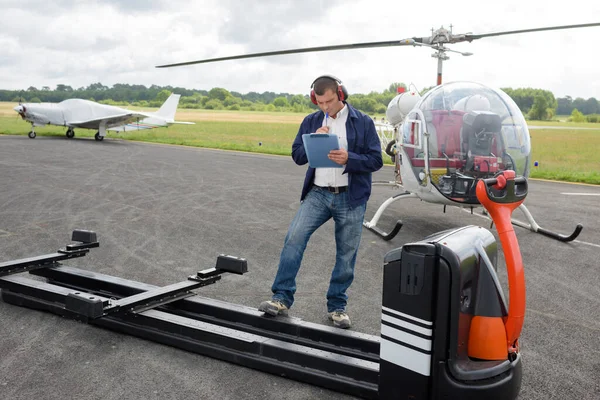 ヘリコプターの予告編の横にクリップボードを持つ労働者 — ストック写真