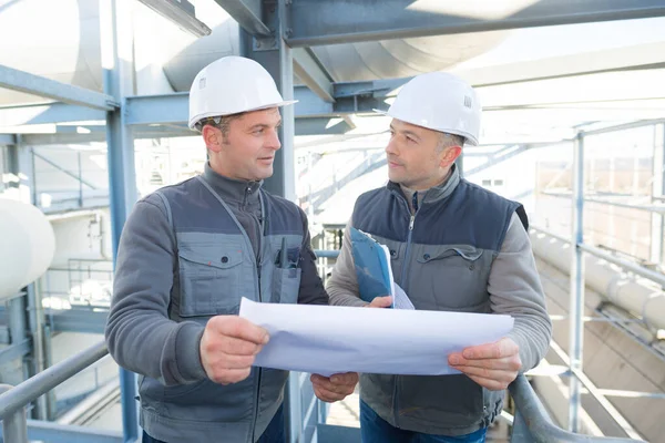 Deux Hommes Discussion Examinant Les Plans Sur Site Industriel — Photo