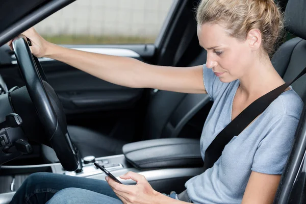女性ドライバーは携帯電話で車を運転し — ストック写真