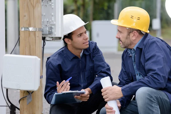 Zwei Männliche Techniker Gespräch Beim Ablesen Von Außenzählern — Stockfoto