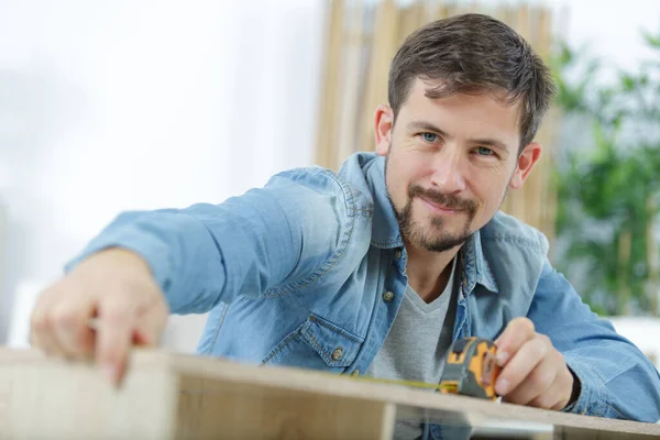 Hombre Mide Una Tabla Madera —  Fotos de Stock