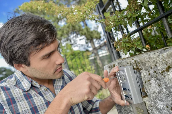 Man Schroeven Beveiligingsinrichting Aan Buitenmuur — Stockfoto