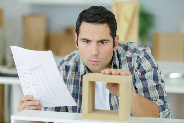 家具を組み立てるためのマニュアルをチェックする男 — ストック写真