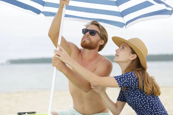 傘のビーチを設定するカップル — ストック写真