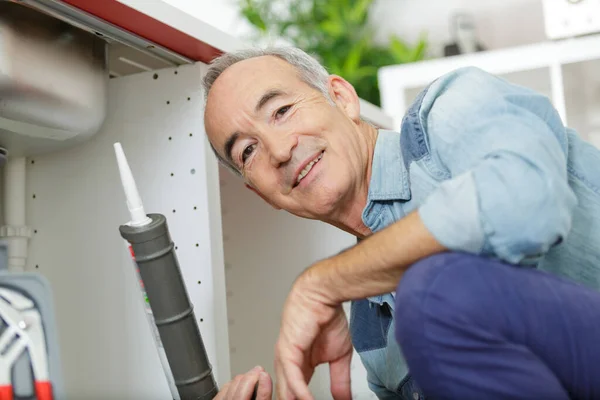 Senior Handyman Applicando Sigillante Siliconico Con Pistola Intorno Lavandino — Foto Stock