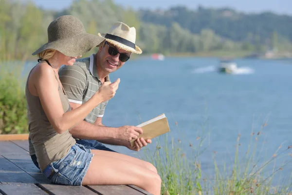 Couple Est Assis Sur Une Jetée Tenant Livre — Photo