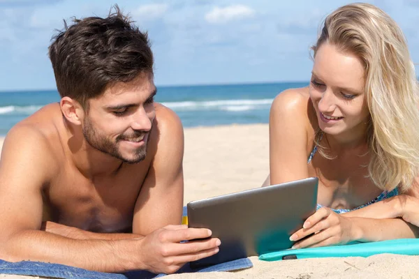 夫妇在海滩上使用平板电脑 — 图库照片
