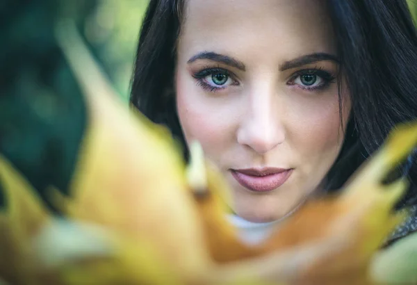 Jolie femme sereine regardant au-dessus des feuilles d'automne — Photo