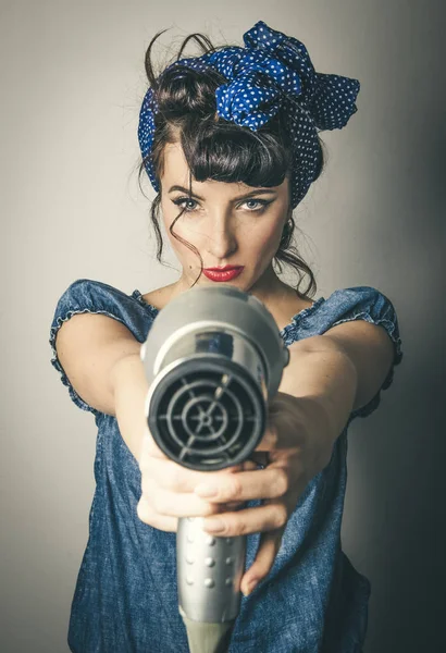 Vrouw in vintage kleding aanwijsapparaat haardroger Stockfoto