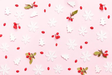 Zarif bir kış geçmişi var. Kırmızı böğürtlen, kar taneleri ve soluk pembe arka planda küçük noel tişörtleri. Noel, kış tatili, yeni yıl konsepti.