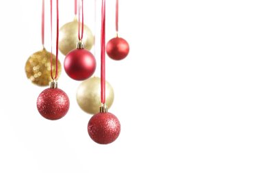 Altın ve kırmızı Noel topları beyaz arka planda asılı duruyor. Büyük parıltılı Noel süsleri.