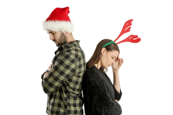 サンタの帽子とトナカイのヘッドバンドを身に着けている厄介な不幸なカップルのスタジオの肖像画 冬休みストレスコンセプト — ストック写真