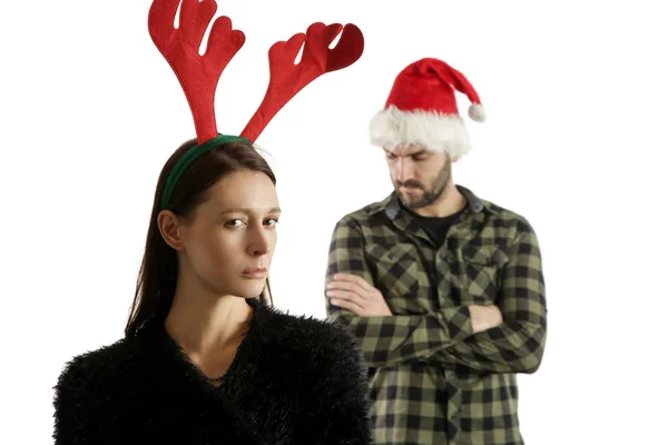 サンタの帽子とトナカイのヘッドバンドを身に着けている厄介な不幸なカップルのスタジオの肖像画 冬休みストレスコンセプト — ストック写真