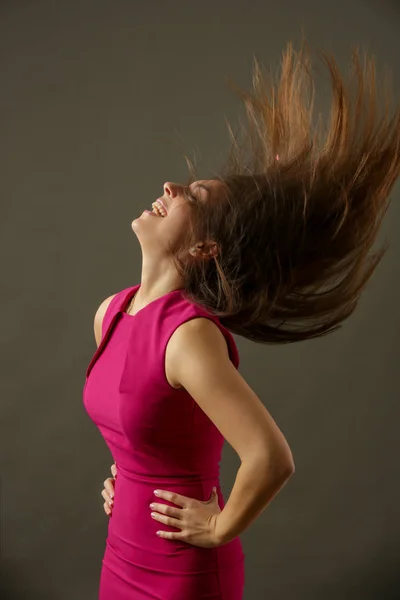 Attractive woman in fuchsia bodicon dress with beautiful brown long hair, studio shot