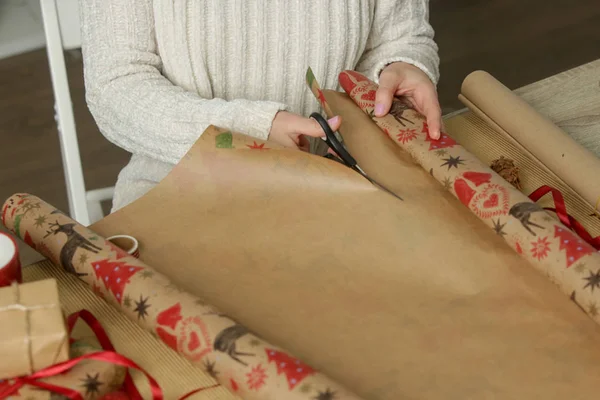 Woman cutting wrapping paper on the desk, holiday season gifting concept