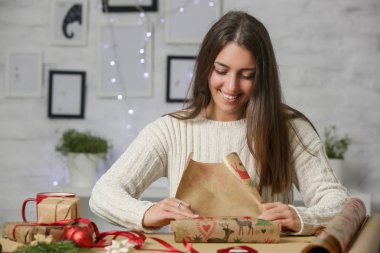Mutlu gülümseyen kadın Noel hediyelerini paketliyor, kış tatilleri, hediye sezonu konsepti