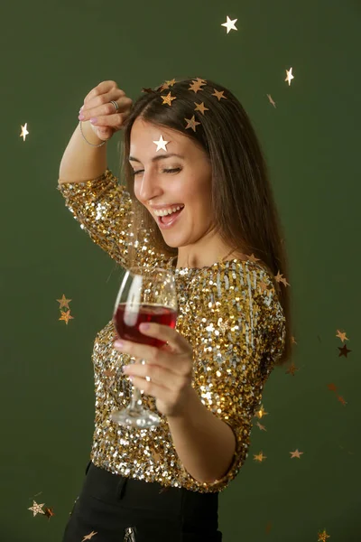 黄金のスパンコールのシャツの魅力的な女性が踊り 赤ワインのガラスを保持します 幸せ若いです美しいです女性楽しいですコンフェッティとパーティー — ストック写真