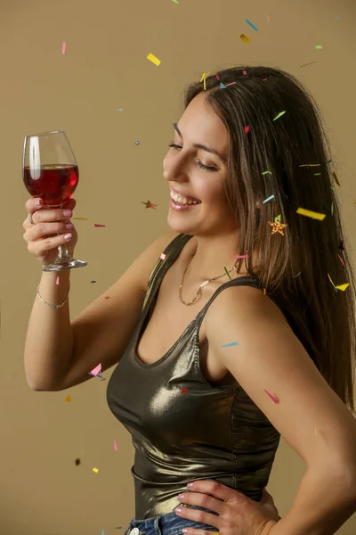 黄金のシャツダンスで魅力的な女性と赤ワインのガラスを保持します 幸せ若いです美しいです女性楽しいですコンフェッティとパーティー — ストック写真