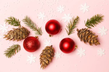 Red Christmas shiny balls and fir twigs on pale pink background. Christmas ornaments arrangement. clipart