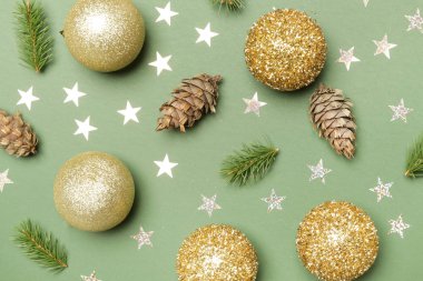 Altın parıltılı Noel süsleri ve yeşil arka planda yıldızlar. Noel, kış tatili, yeni yıl konsepti.